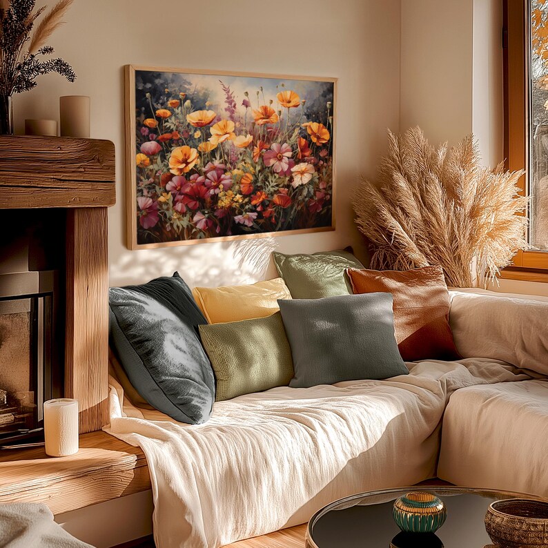 Op de afbeelding: Een woonkamer met een bank bekleed met witte linnen stof. De bank heeft verschillende kussens in verschillende kleuren en texturen, waaronder groen, bruin en grijs. Een schilderij met een bloemstuk met oranje, gele en rode bloemen hangt aan de muur boven de bank.