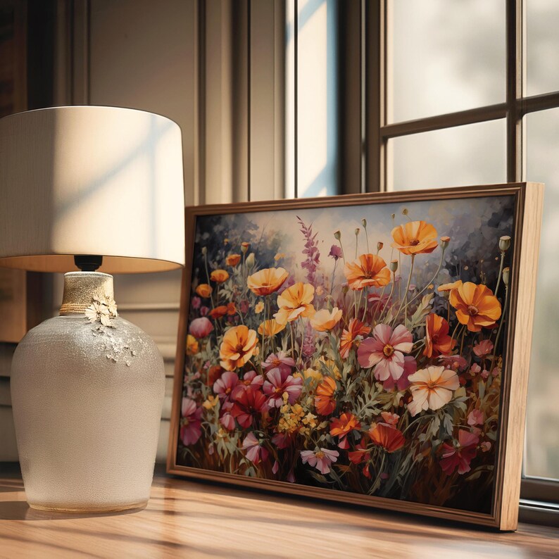 Op de afbeelding: Een ingelijst schilderij van een veld met wilde bloemen in tinten oranje, geel, roze en rood. De bloemen bloeien en de achtergrond is een zachte blauwe lucht.
