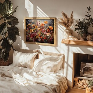 Op de afbeelding: Een ingelijst schilderij van een kleurrijk bloemstuk met verschillende bloemen, waaronder klaprozen, in tinten rood, oranje, geel en roze. Het schilderij hangt aan een witte muur boven een bed met wit linnen beddengoed.