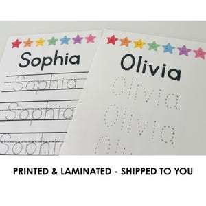 May include: Two white laminated sheets with the names "Sophia" and "Olivia" printed in black. Each sheet has a row of colorful smiling star graphics. The "Sophia" sheet has lines for tracing. The text "PRINTED & LAMINATED - SHIPPED TO YOU" is at the bottom.
