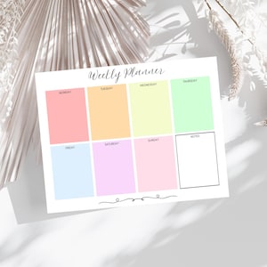 Peut inclure: Un planificateur hebdomadaire avec des cases aux couleurs pastel pour chaque jour de la semaine, de lundi à dimanche. Le planificateur comprend également une section notes. Les mots "Weekly Planner" sont écrits en cursive en haut.