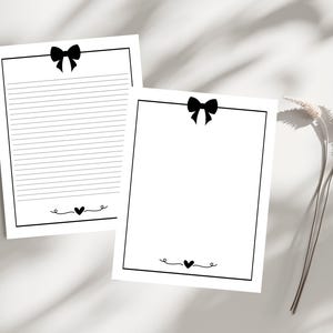 Op de afbeelding: Twee bedrukbare briefpapierbladen met zwarte randen en een zwarte strik bovenaan. Elk blad heeft een klein hartje onderaan.