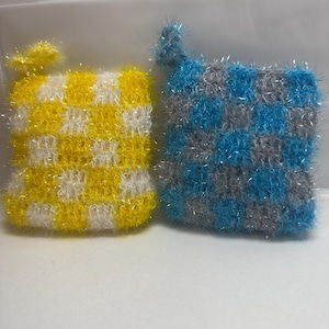 May include: Two knitted dishcloths, one yellow and white, the other blue and gray. Both have a checkered pattern and sparkly threads.