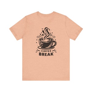 Op de afbeelding: Een perzikkleurig T-shirt met een zwarte afbeelding van een kopje koffie met stoom die eruit opstijgt. De tekst "COFFEE BREAK" staat onder het kopje.