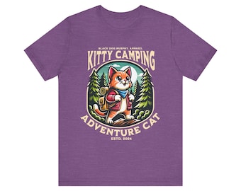 May include: Purple t-shirt with a graphic of an orange cat wearing a backpack and walking through a forest. The text "Kitty Camping Adventure Cat" is in a circle around the cat. The text "Black Dog Murphy Apparel" and "Estd. 2024" are also on the shirt.