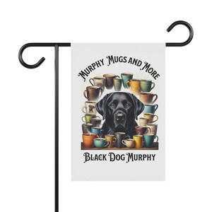 May include: A black Labrador Retriever dog with a white background. The dog is surrounded by colorful coffee mugs with the text "Murphy Mugs and More" and "Black Dog Murphy".