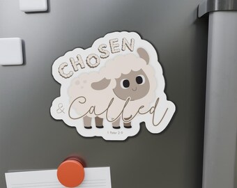 May include: A white and beige magnet with a cartoon sheep illustration. The magnet has the words "CHOSEN & CALLED" in a script font. The text "1 Peter 2:9" is at the bottom. The magnet is on a gray surface.
