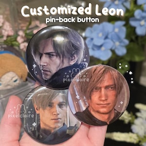 May include: Three circular pin-back buttons featuring portraits of a character with light brown hair. Each button displays a different facial expression of the same individual. The buttons have a glossy finish and include small white graphic accents.