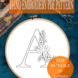 May include: A black and white embroidery pattern of the letter A with floral embellishments. The pattern is displayed in a wooden embroidery hoop. The text "PDF BUNDLE 26 Letters" is displayed in a circle with an orange background.