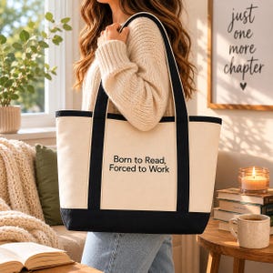 May include: Cream-colored tote bag with black trim and handles. The bag features the text "Born to Read, Forced to Work" in black. The bag is carried by a person wearing a cream-colored sweater.