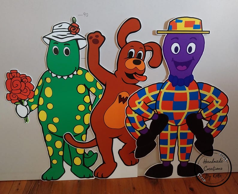 May include: Four colourful cardboard cutouts of characters from the children's television show 'The Wiggles'. The characters are a green dinosaur wearing a pink hat, a red dog, a purple octopus wearing a yellow and red hat, and a yellow and red striped character with a purple head.