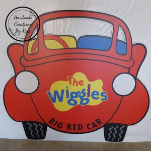 May include: A red car cutout with the words "The Wiggles Big Red Car" on the side. The car has a yellow steering wheel and blue seats.