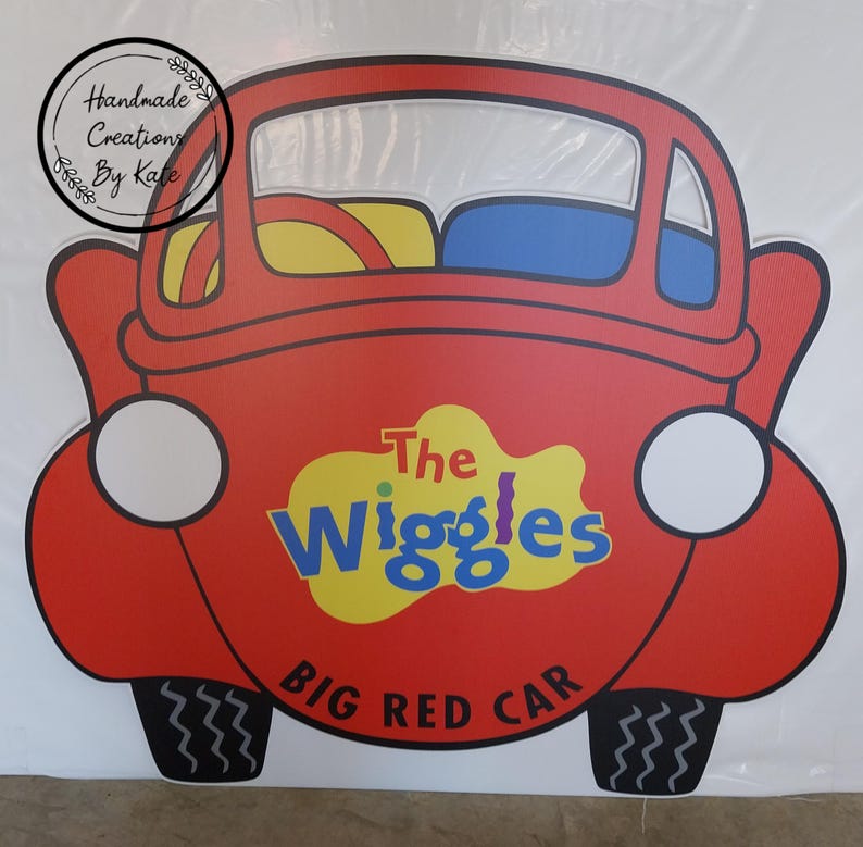 May include: A red car cutout with the words "The Wiggles Big Red Car" on the side. The car has a yellow steering wheel and blue seats.