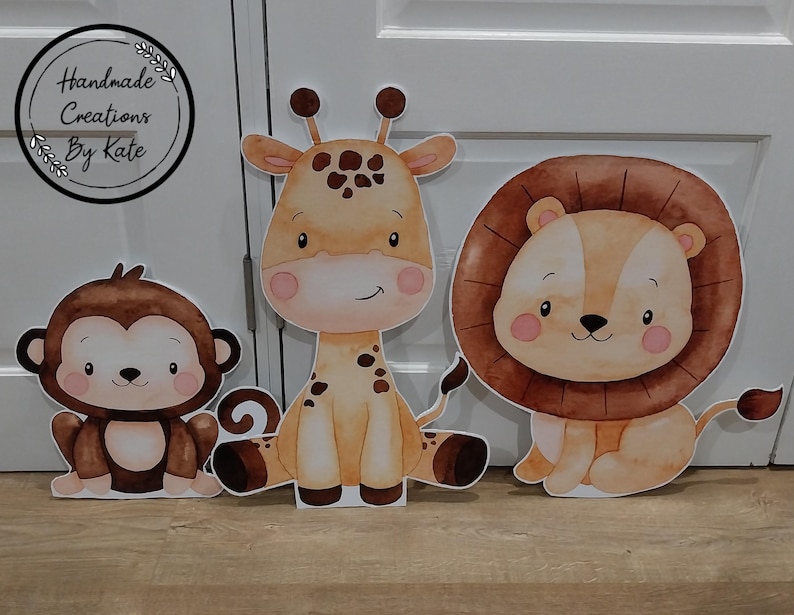May include: Three adorable animal cutouts: a brown monkey, a brown and orange giraffe, and a brown lion with a mane. The cutouts are perfect for a jungle-themed party or nursery.
