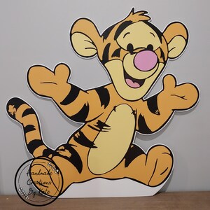Puede incluir: Un recorte de cart&oacute;n del personaje Tigger de Winnie the Pooh. Tigger es naranja y negro con la barriga amarilla y la nariz rosa. Est&aacute; de pie con los brazos extendidos y las piernas separadas. El recorte est&aacute; hecho de cart&oacute;n y est&aacute; listo para ser usado en una fiesta u otro evento.