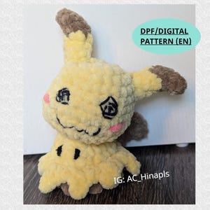 Może przedstawiać: Ręcznie robiona pluszowa lalka Mimikyu w kolorze żółtym i brązowym, z czarnymi haftowanymi oczami i ustami oraz różowymi policzkami. Lalka ma teksturowany, puszysty wygląd. Tekst na zdjęciu brzmi "DPF/DIGITAL PATTERN (EN)" i "IG: AC_Hinapls".