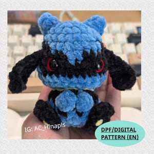 Könnte beinhalten: Ein handgefertigtes blau-schwarzes Häkeltier mit roten Augen. Das Plüschtier hat ein detailliertes Design und ein strukturiertes Aussehen. Das Spielzeug ist eine Figur aus einer beliebten Franchise. Das Bild enthält auch den Text "DPF/DIGITAL PATTERN (EN)".