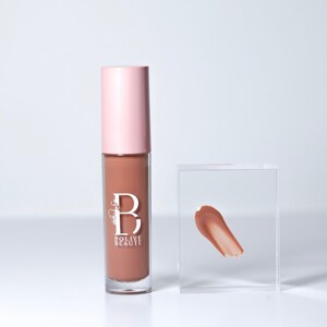 May include: A clear tube of lip gloss with a pink cap. The tube has a white label with the text "Bolive Beaute" and a stylized "B". A small sample of the lip gloss is shown on a clear acrylic square.