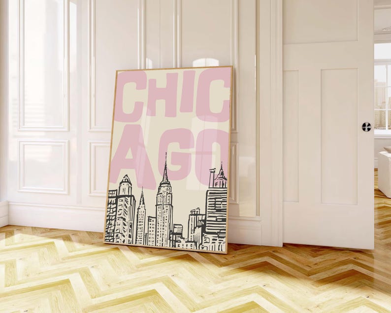 May include: A framed art print featuring the word "CHICAGO" in pink block letters over a black and white skyline illustration. The artwork is displayed against a cream background, with a light wood frame.