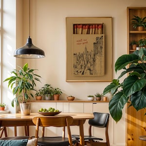 Puede incluir: Escena de comedor con mesa y sillas de madera, l&aacute;mpara colgante negra y obra enmarcada de una caja de cerillas con el texto "meet me new york". Plantas en macetas y un mueble de madera completan el interior.