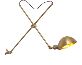 May include: A brass wall-mounted light fixture with two adjustable arms and a dome-shaped shade. The light is turned on and emits a warm glow.