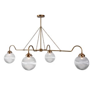 May include: A brass-toned, four-light chandelier with clear, ribbed glass globe shades. The fixture is suspended from the ceiling by chains and a central rod. The curved arms and globe shape give it a vintage feel.