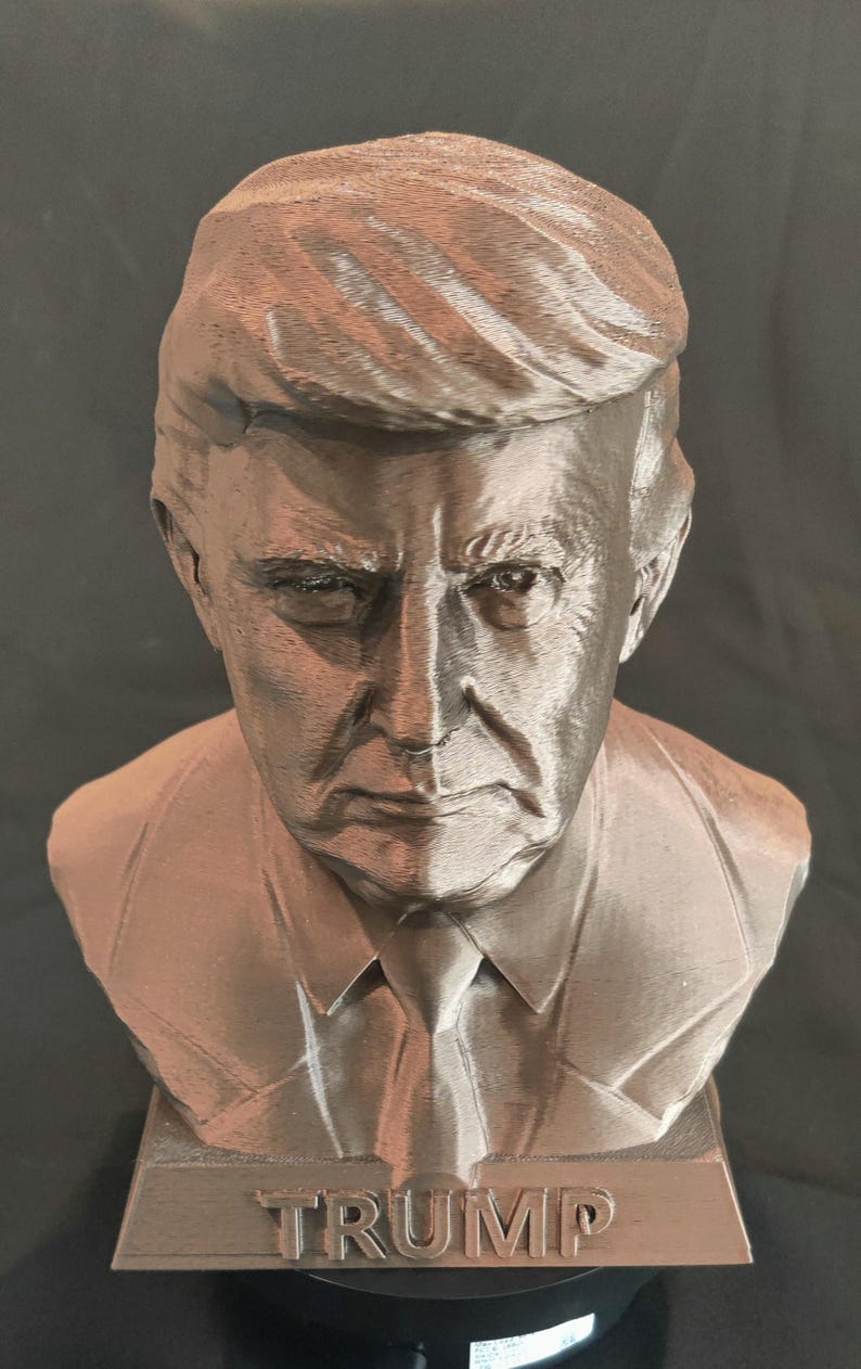 May include: A bronze bust of Donald Trump with the word "TRUMP" inscribed on the base.