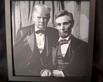 May include: A framed black and white artwork featuring a split-face portrait of Donald Trump and Abraham Lincoln. Both figures are depicted wearing formal suits with bow ties, presented in a square black frame against a dark background.