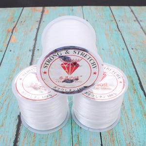 May include: Three spools of clear, stretchy crystal string. The spools have a clear plastic casing with a label that reads "STRONG & STRETCHY CRYSTAL STRING" in English and Japanese. The string is 100% polyurethane.