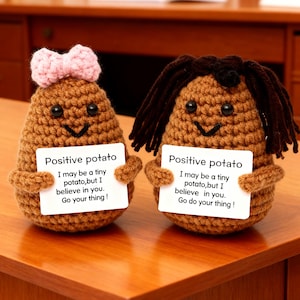 Puede incluir: Dos figuras de patata de ganchillo, una con un lazo rosa y la otra con pelo de hilo marrón, cada una sosteniendo un cartel que dice "Positive potato". Los carteles tienen un mensaje motivador.