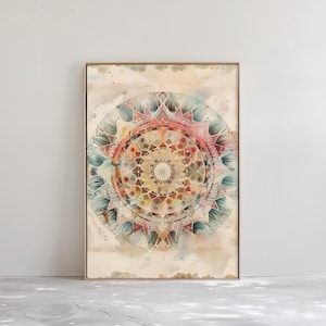 Op de afbeelding: Een ingelijste aquarelprint met een gedetailleerd mandala-ontwerp. Het kunstwerk toont een symmetrisch patroon met een centraal focuspunt, met tinten roze, geel, blauw en groen. De print zit in een dunne, lichtbruine lijst, voor wanddecoratie, ongeveer 50 x 70 cm.