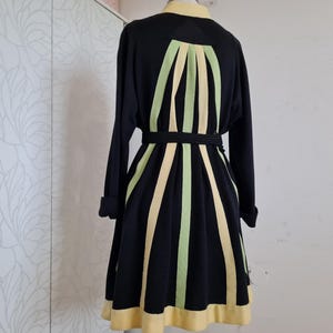 May include: Black dress with long sleeves, a yellow collar, and a matching hem. The dress features vertical stripes in light green and yellow, with a black belt at the waist. The dress is displayed on a mannequin.