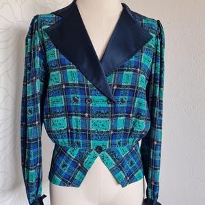 May include: A blue and green plaid blazer with a black satin collar and cuffs. The blazer has a double-breasted closure and a fitted waist.