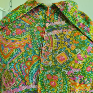 Pu&ograve; includere: Un vestito vintage con stampa paisley in tonalit&agrave; di verde, rosa, arancio e giallo. Il vestito ha una cerniera sul retro.