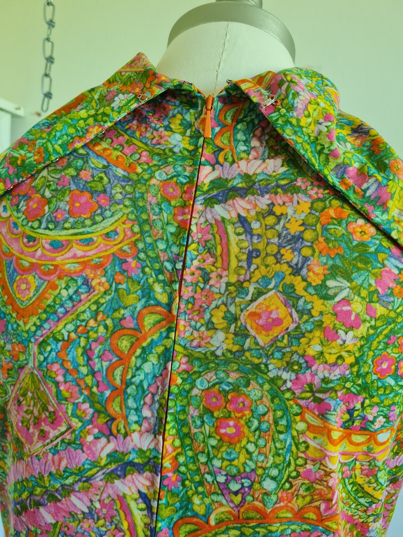 Pu&ograve; includere: Un vestito vintage con stampa paisley in tonalit&agrave; di verde, rosa, arancio e giallo. Il vestito ha una cerniera sul retro.