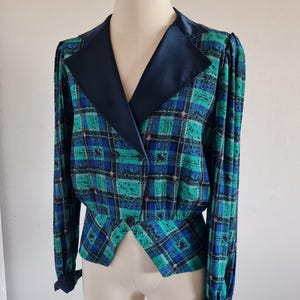 May include: A blue and green plaid blazer with a black satin collar. The blazer has a double-breasted closure and a fitted silhouette.