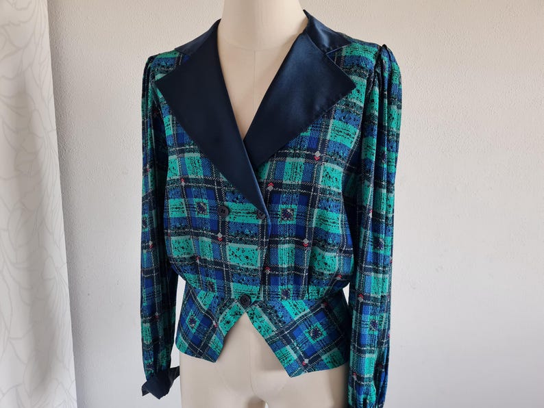 May include: A blue and green plaid blazer with a black satin collar. The blazer has a double-breasted closure and a fitted silhouette.