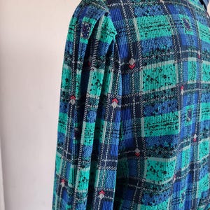 May include: A blue and green plaid dress with a ruffled collar and puffed sleeves.