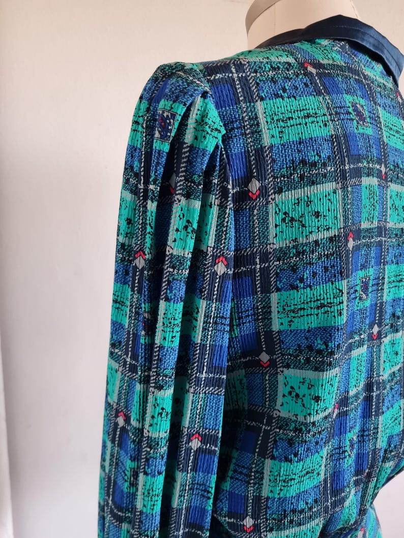 May include: A blue and green plaid dress with a ruffled collar and puffed sleeves.