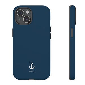 May include: A dark blue smartphone case featuring a white anchor graphic and the text MOIN printed below it. The case has a dual-camera cutout on the back and a slim profile, shown from both the rear and side angles to display the design and shape.