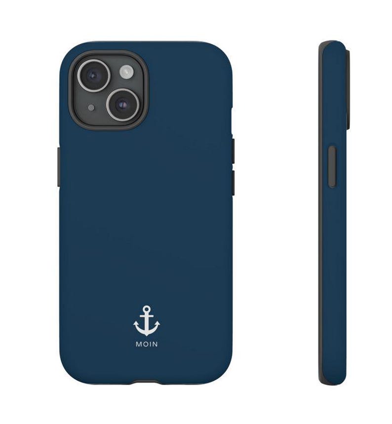 May include: A dark blue smartphone case featuring a white anchor graphic and the text MOIN printed below it. The case has a dual-camera cutout on the back and a slim profile, shown from both the rear and side angles to display the design and shape.