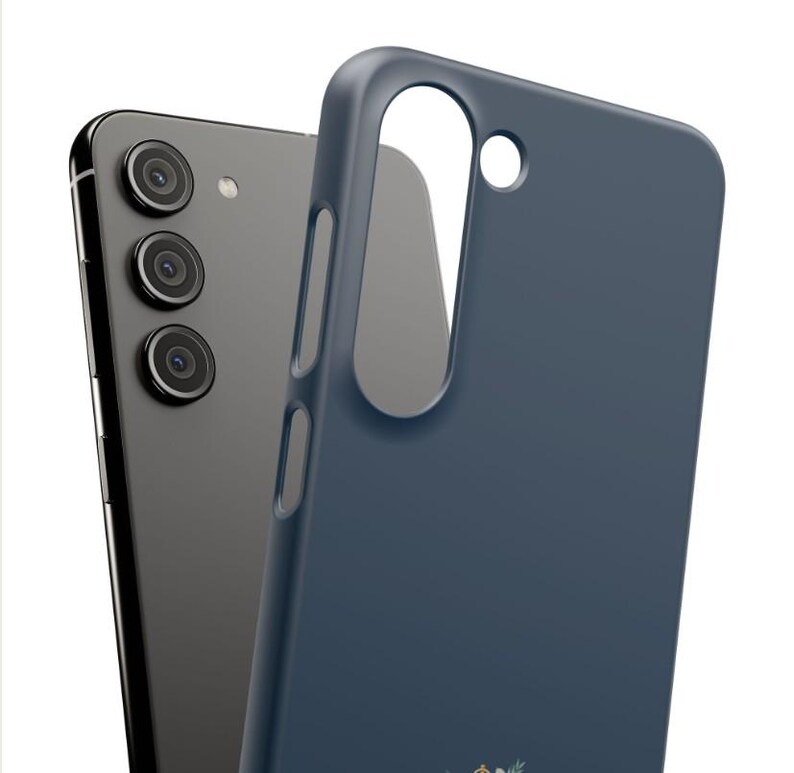 Puede incluir: Un tel&eacute;fono inteligente gris oscuro con tres lentes de c&aacute;mara traseros junto a una funda protectora de color azul marino s&oacute;lido. La funda presenta un gran recorte vertical para la c&aacute;mara y aberturas laterales para botones y puertos.