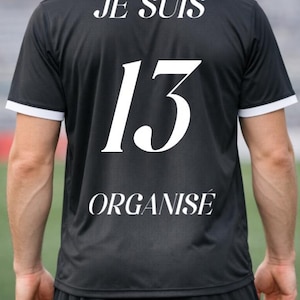 May include: Black athletic jersey with white trim and the number 13 in large white numerals. The words "JE SUIS" and "ORGANISÉ" are printed above and below the number.