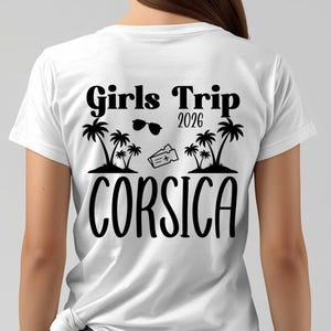 Peut inclure: T-shirt blanc avec un motif noir au dos. Le motif comprend le texte "Girls Trip 2026 CORSICA" ainsi que des illustrations de palmiers, de lunettes de soleil et d'un billet d'avion.
