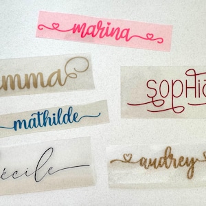Puede incluir: Seis etiquetas de nombre personalizadas con diferentes nombres, incluyendo "Emma", "Sophia", "Cecile", "Mathilde", "Marina" y "Audrey". Las etiquetas están impresas en hojas adhesivas transparentes.