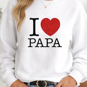 Peut inclure: Sweat-shirt blanc avec l'inscription "I ❤️ PAPA" en noir et rouge. Le cœur rouge a une texture pailletée. Le sweat-shirt est de style décontracté, adapté au quotidien.