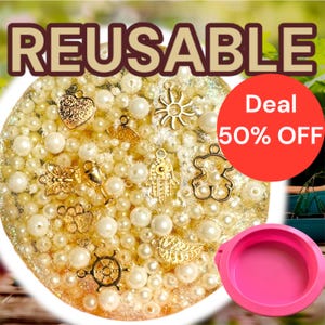 May include: A round, gold-glittered resin base filled with white pearls and gold charms. Charms include a heart, sun, butterfly, Hamsa hand, bear, and leaf. The word "REUSABLE" is at the top, and a red circle with "Deal 50% OFF" is on the right.