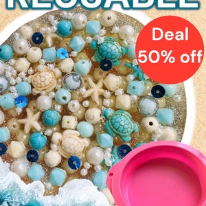 May include: A close-up of a decorative resin piece with a beach theme. It features various beads, including white pearls, turquoise, and blue beads, along with turtle and starfish charms. The word "REUSABLE" is at the top, and a red circle indicates a 50% off deal.