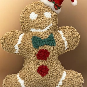 May include: A plush gingerbread man with a red Santa hat, green bow tie, and red buttons. The gingerbread man is made of a soft, textured brown material with white accents. A festive holiday decoration.
