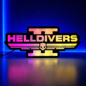 May include: A black and neon sign with the text "HELLDIVERS" in a stylized font. The sign features a skull emblem and a wing design, illuminated with a gradient of pink, yellow, and orange lights. The background is a dark blue.